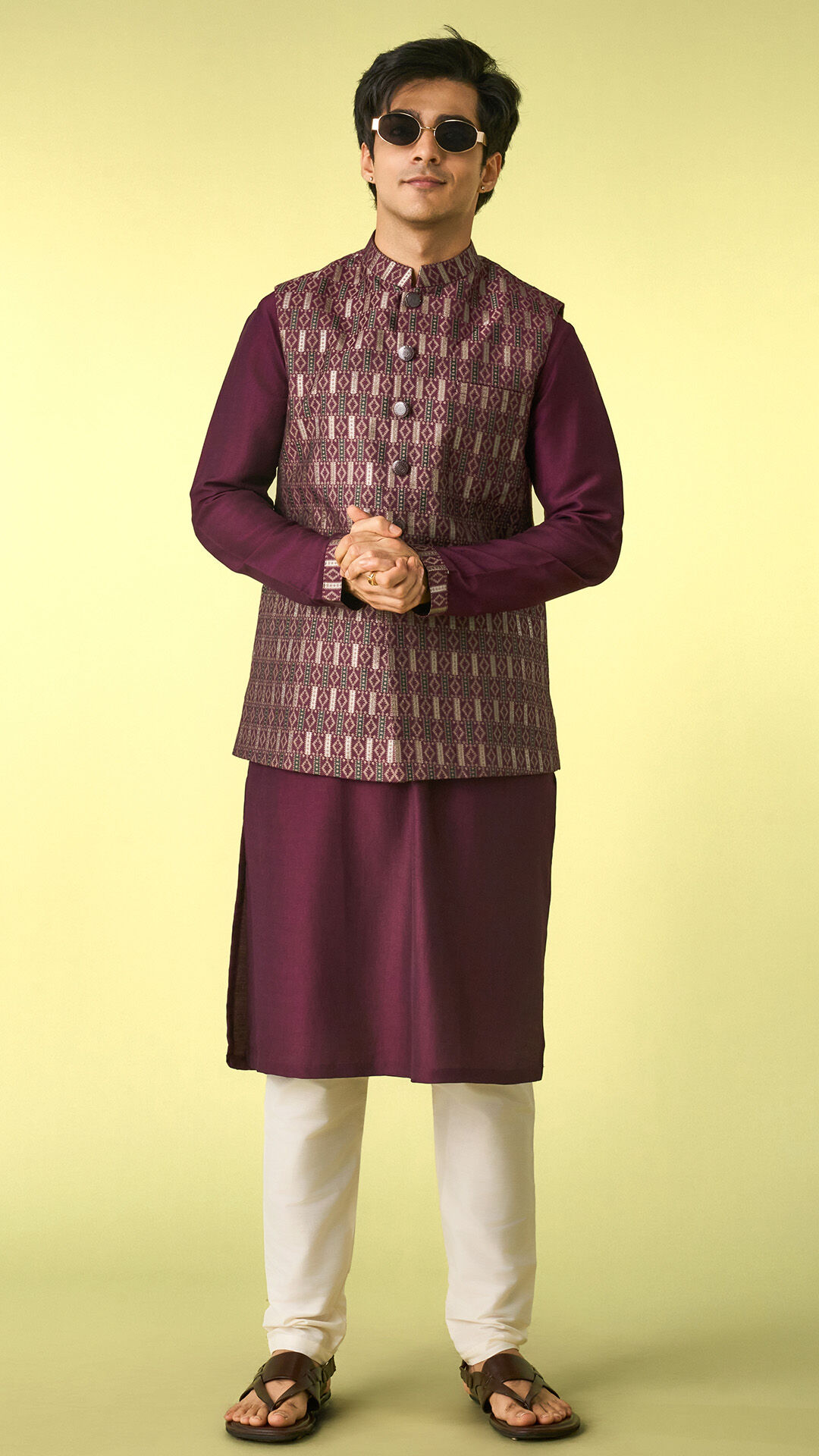 Man wearing a deep plum kurta with a patterned Nehru jacket and ivory churidar, illustrating how a tailored fit and structured layering create a balanced, proportionate look for shorter men.